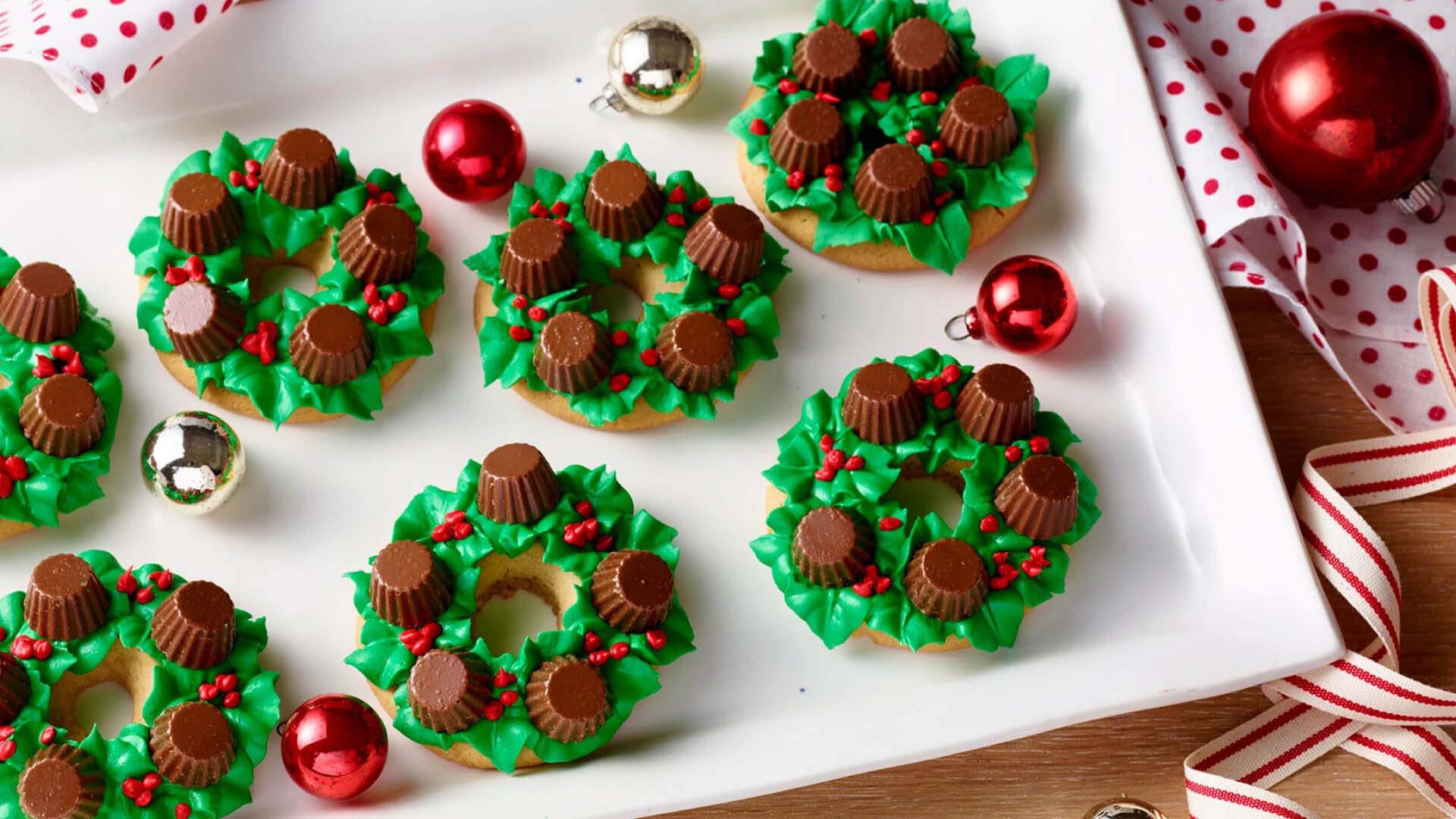 tray of mini wreath cookies topped with icing, sprinkles, and reeses miniatures peanut butter cups