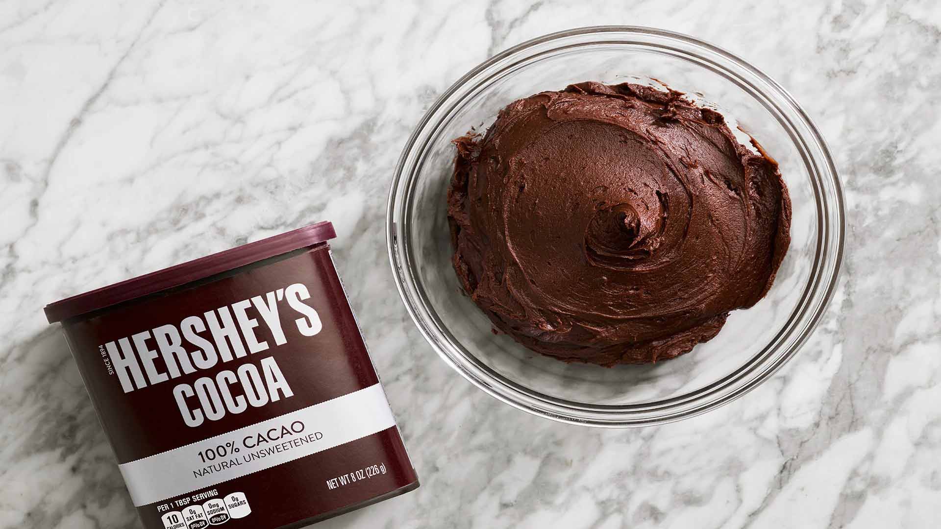 glass bowl full of frosting made with hersheys cocoa