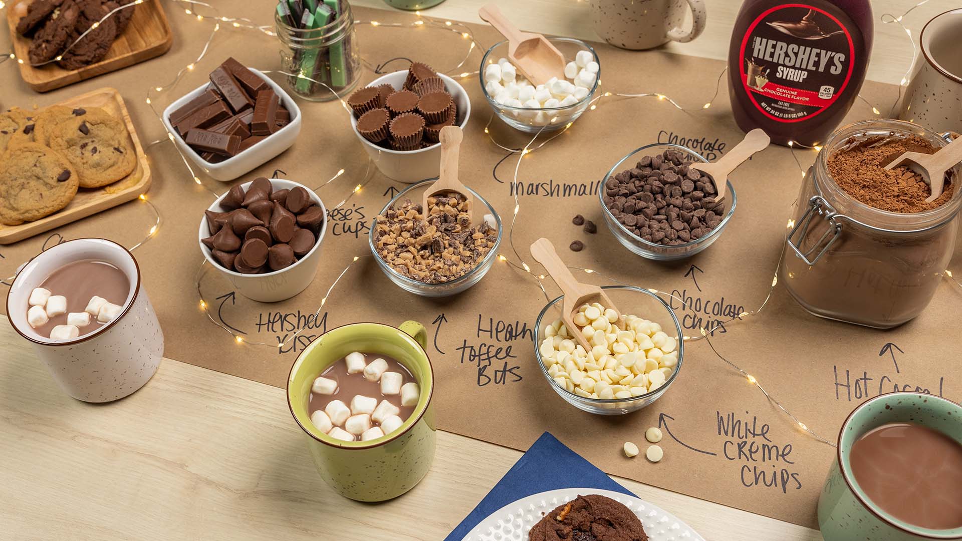 hot chocolate bar filled with bowls of assorted hersheys candies and toppings