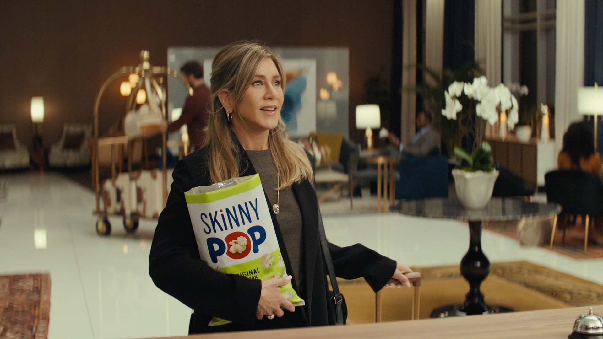 jennifer aniston checking into a hotel while eating skinnypop original popcorn