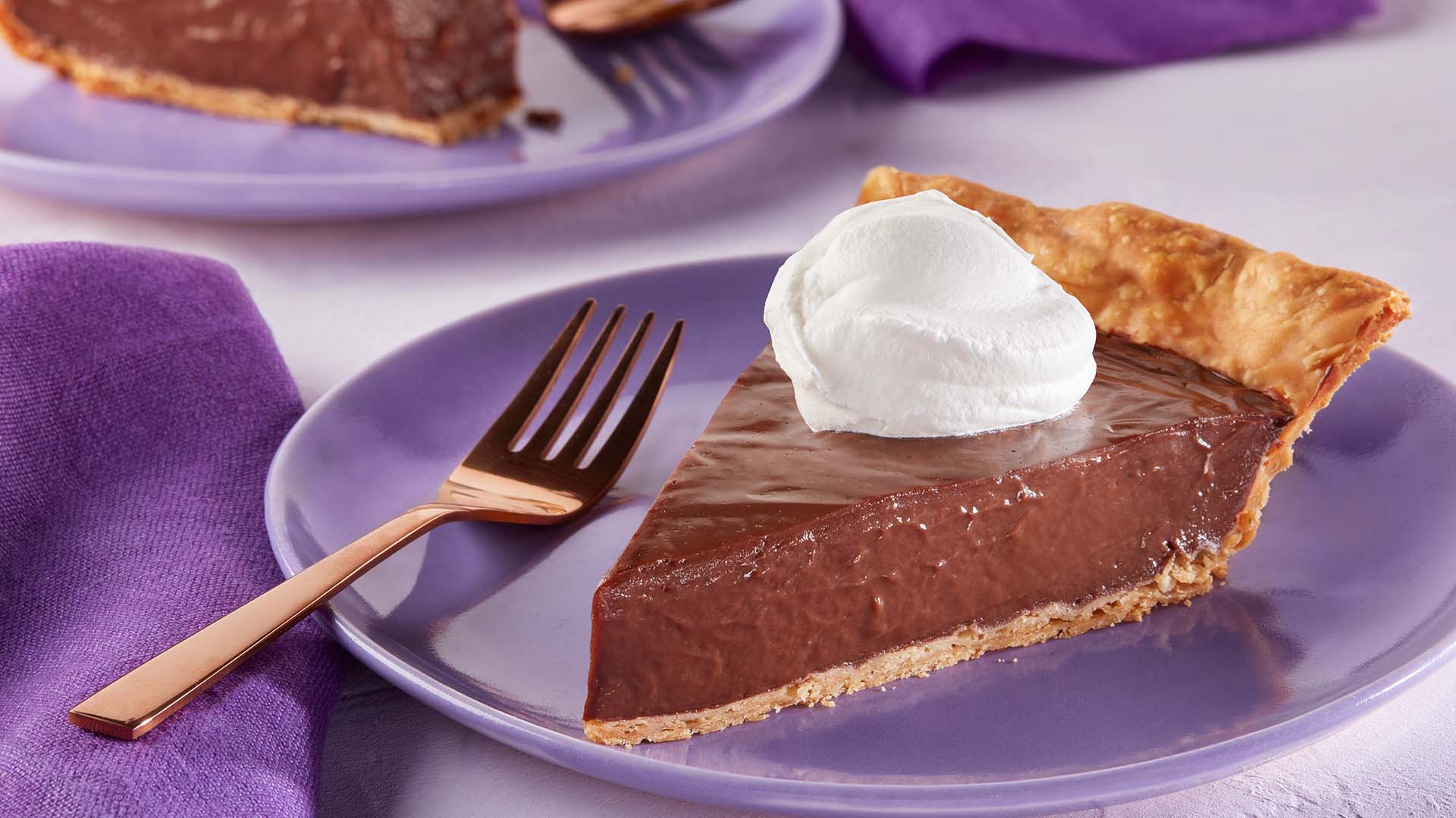 slice of hersheys cocoa creme pie topped with whipped cream on a serving dish