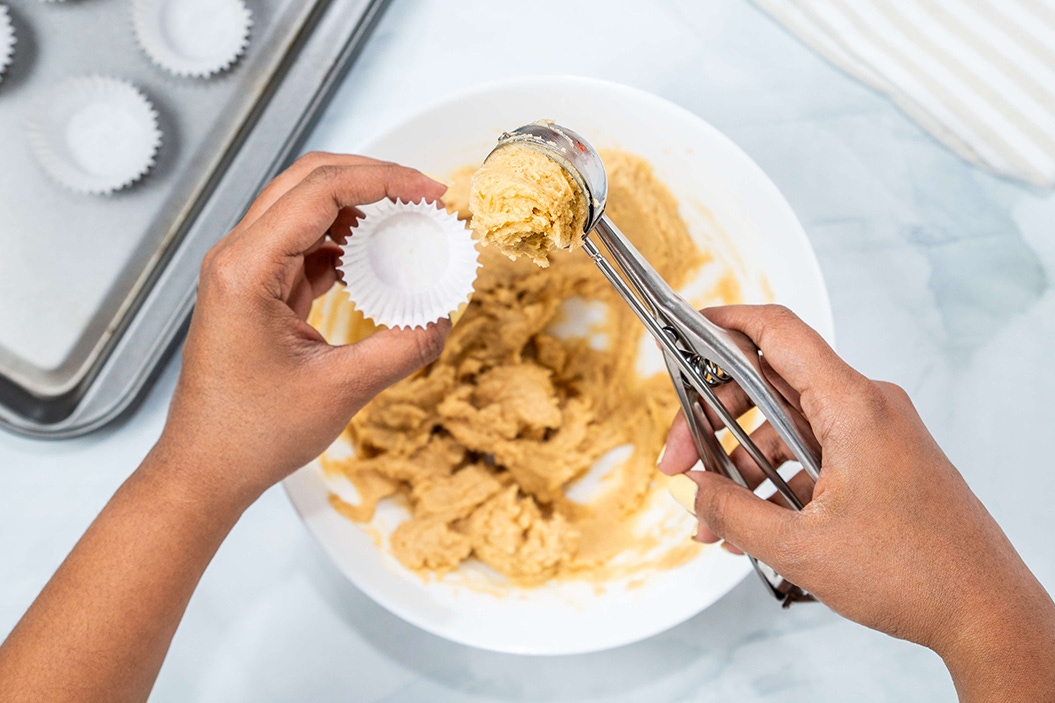 batter being scooped into muffin liners