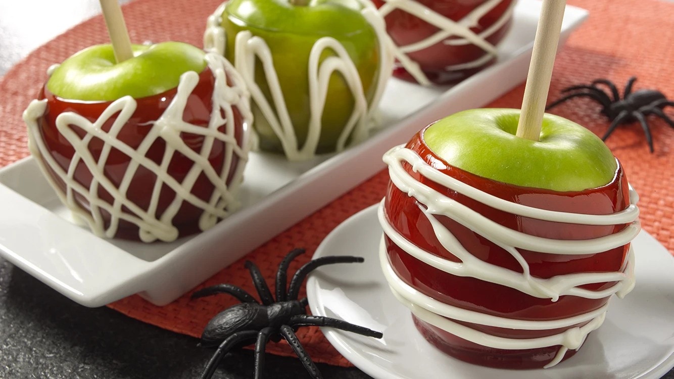 plated jolly rancher candy apples decorated with white chocolate spider webs