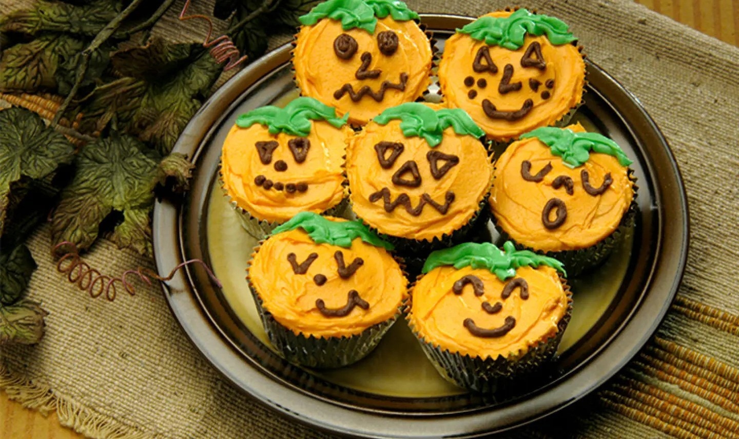 plate of cupcakes decorated like jack o lanterns