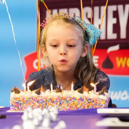 little girl blowing out candles on birthday cake